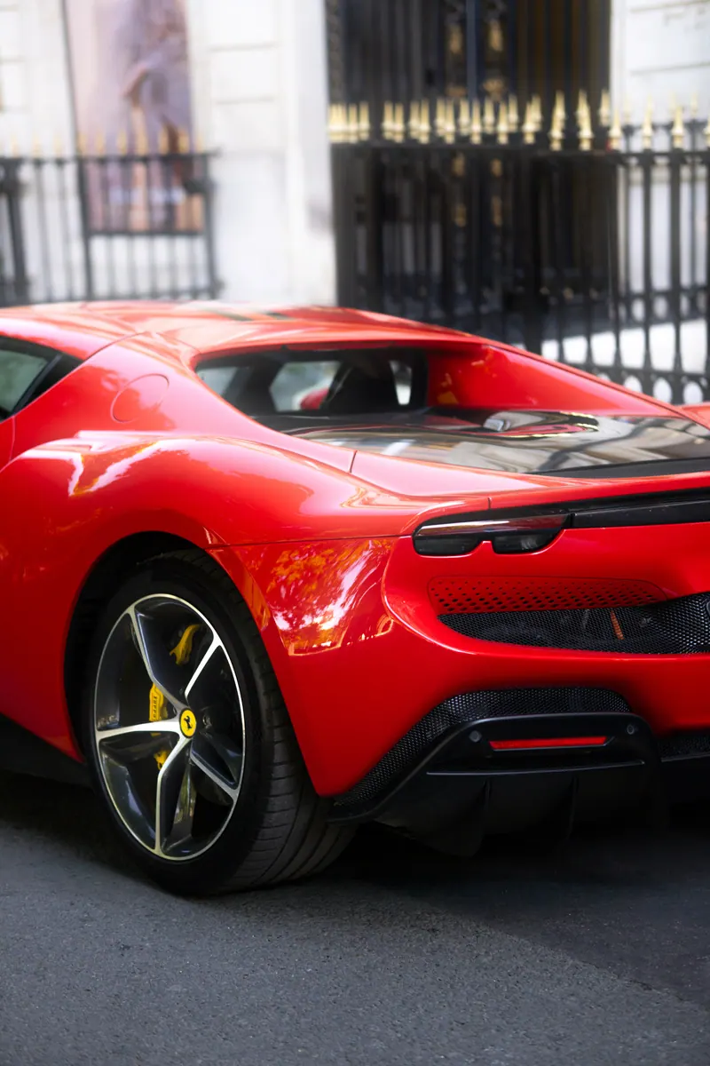 Ferrari rouge stationnée devant une grille en fer forgé
