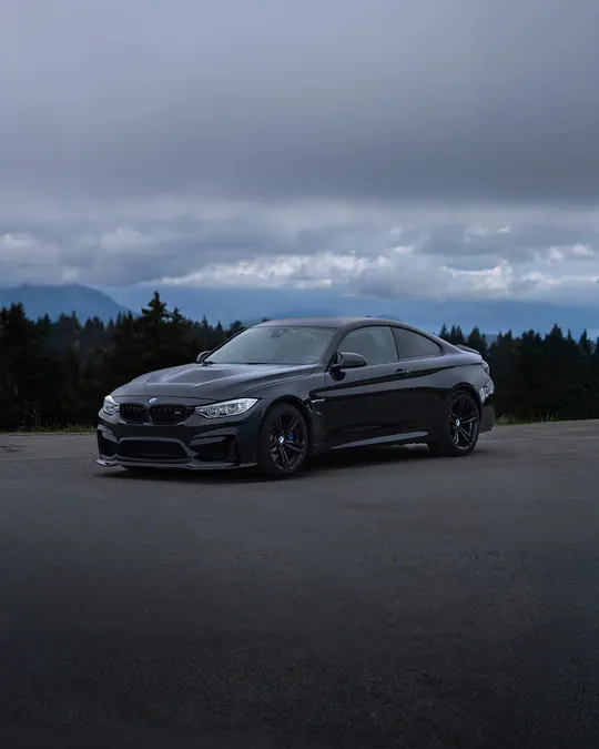 BMW noire sous un ciel nuageux de montagne