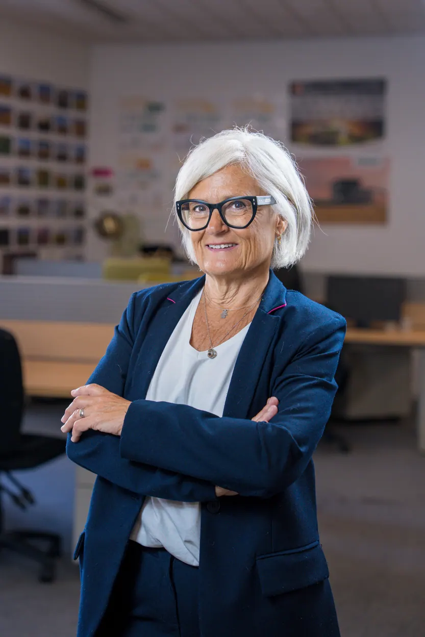 Portrait corporate debout au bureau, bras croisés : collaboratrice en veste marine