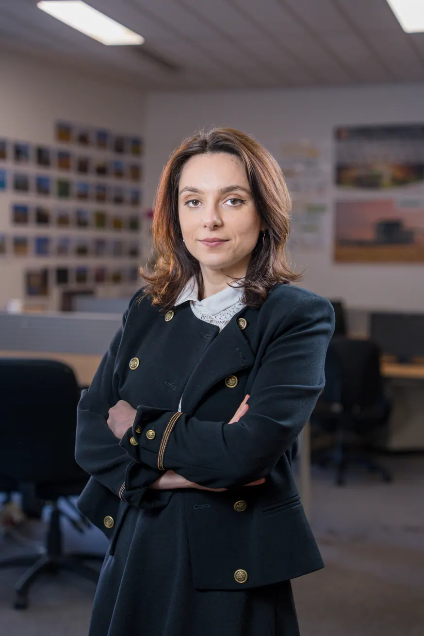 Portrait corporate debout au bureau, bras croisés : collaboratrice en veste sombre