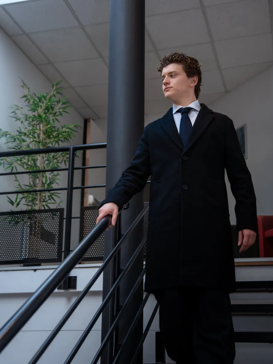 Homme en manteau long près d'une rambarde