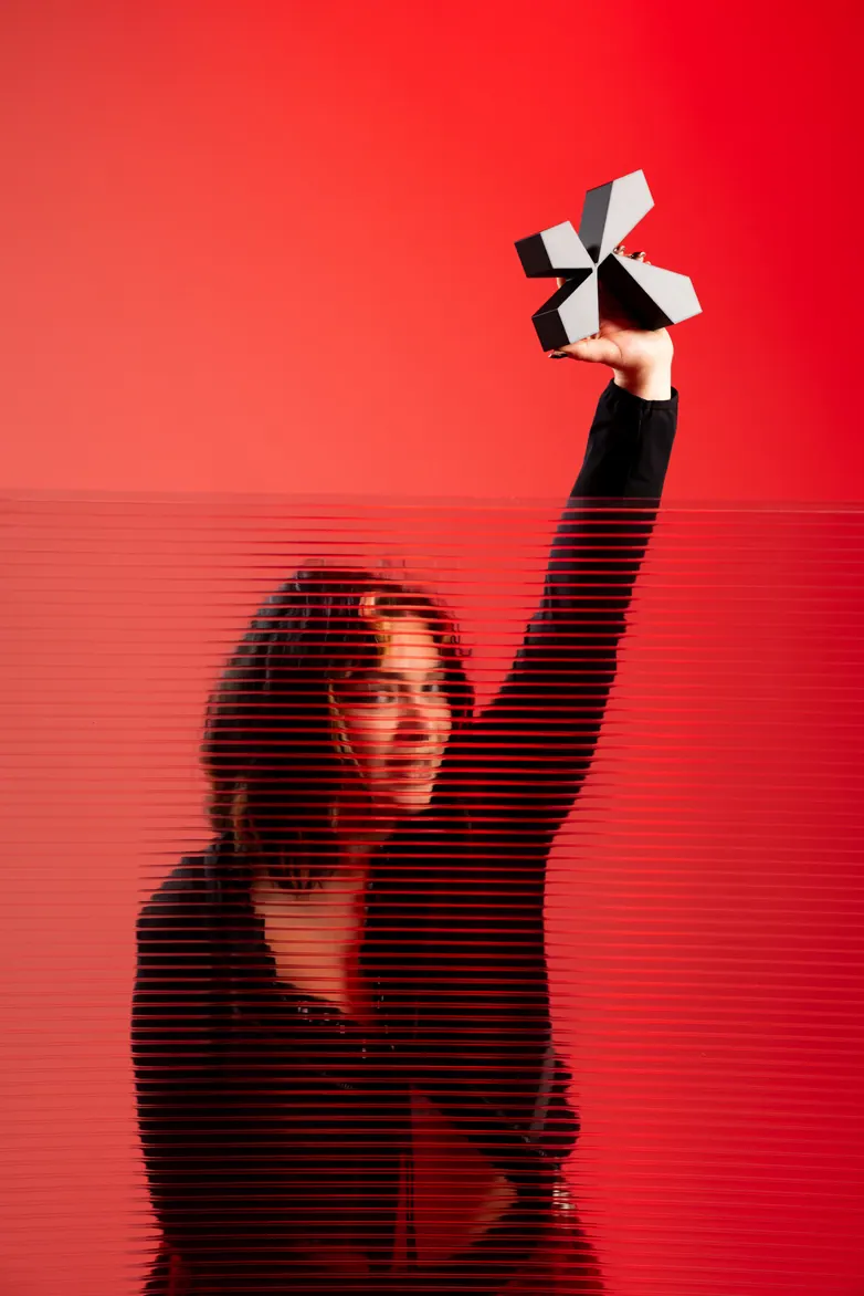 Femme sur fond rouge, objet levé à bout de bras