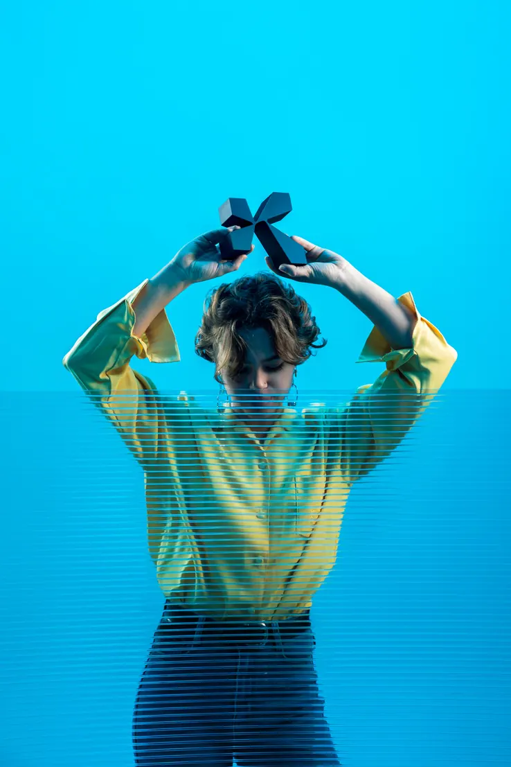 Femme sur fond bleu, mains sur la tête
