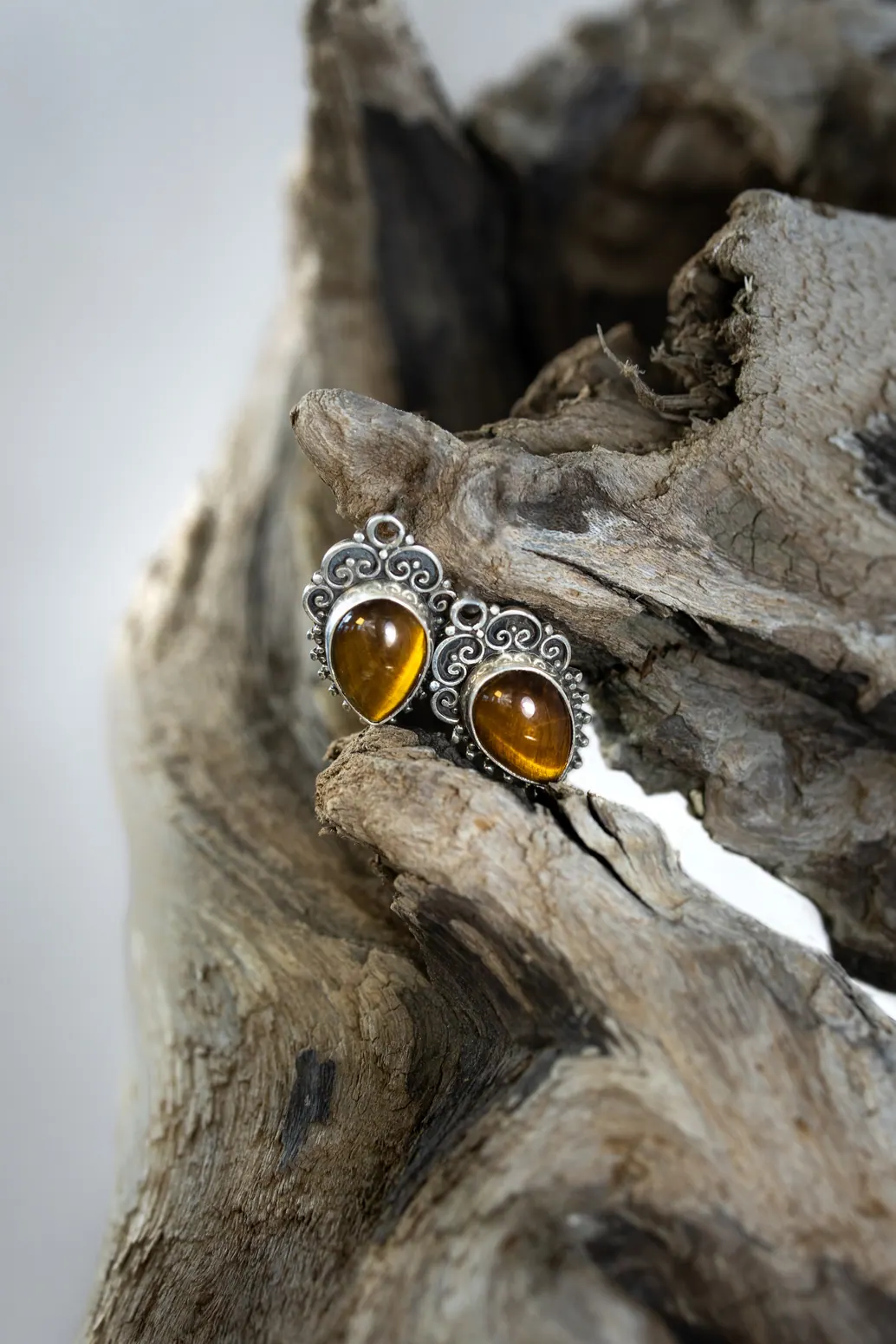 Boucles d'oreilles ambre posées sur du bois flotté